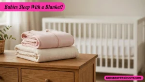 When can babies sleep with a blanket, shown by an empty crib with only a fitted sheet and a folded blanket on a nearby chair